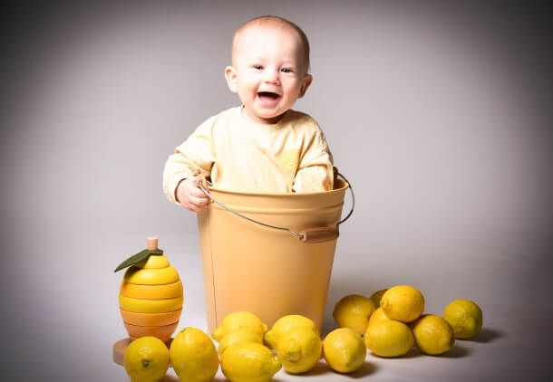 Bebis i hink omgiven av citroner, barnfotografering.