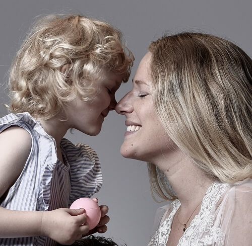Litet barn med sin leende mamma, familjefotografering i studio.