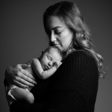 Mamma som håller sin nyfödda bebis tätt intill, svartvit bild