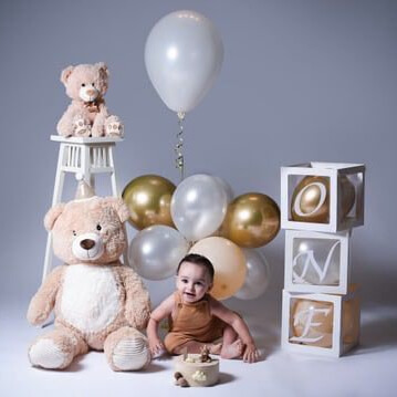 "Smash the cake"-fotografering med ett barn omgiven av gosedjur, ballonger och bokstavsklossar som bildar ordet "ONE"